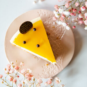 A slice of cake with a yellow glaze and small chocolate decorations